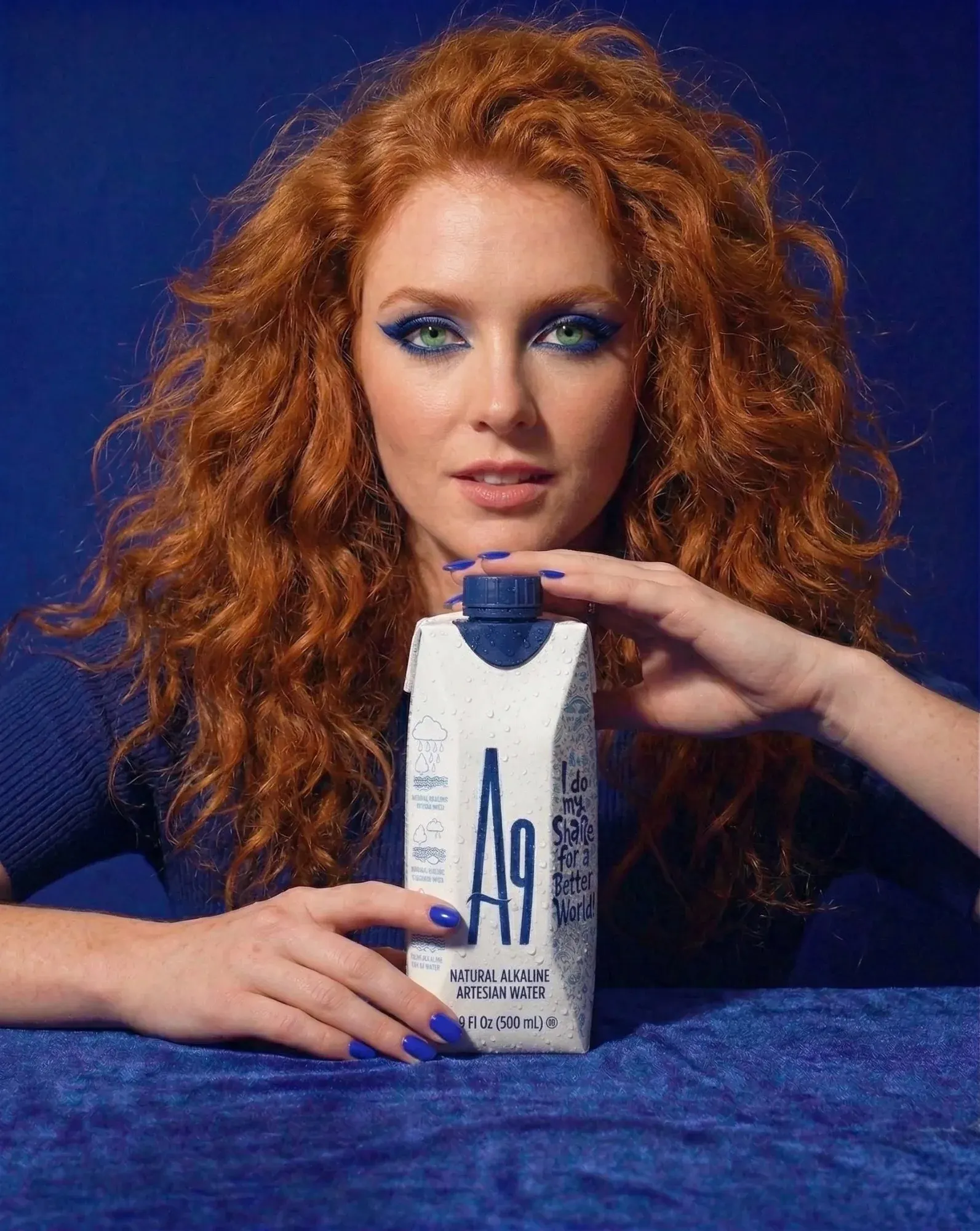 Woman holding an A9 alkaline water carton against a deep blue backdrop